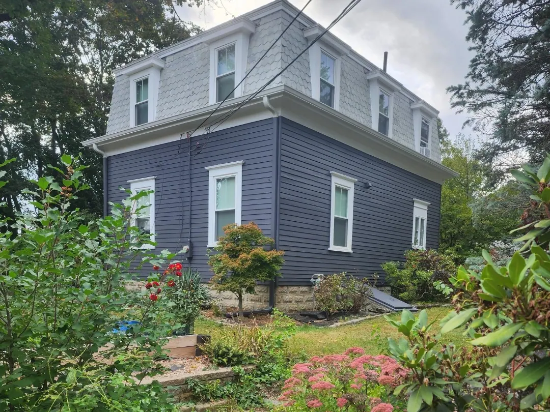 After: the same mansard-roof house painted slate blue with white trim and window casings